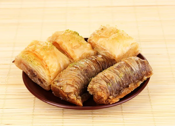 Sweet baklava on plate on bamboo mat — Stock Photo, Image