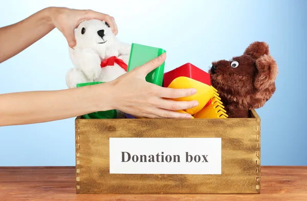 Caixa de doação com crianças brinquedos no fundo azul close-up — Fotografia de Stock