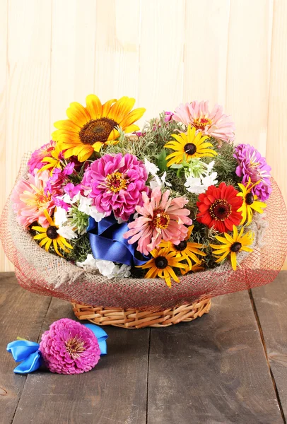 Beautiful bouquet of bright flowers in sacking on wooden background — Stock Photo, Image