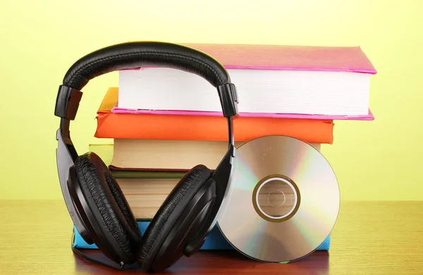Headphones on books on wooden table on yellow background — Stock Photo, Image