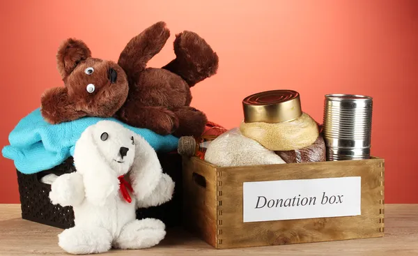 Donatie vakken met kleding en voedsel op rode achtergrond close-up — Stockfoto