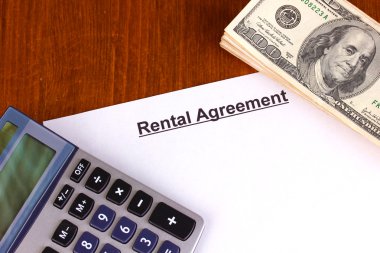 Rental agreement with dollars on wooden background close-up clipart