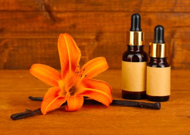 Vanilla pods with essential oil on wooden background close-up