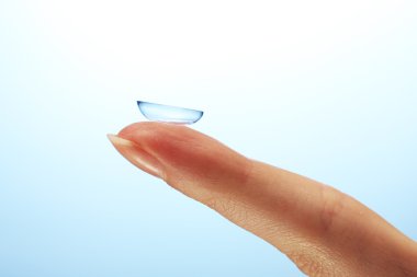 Contact lens on finger on blue background clipart