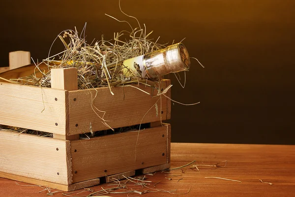 Flaska bra vin i låda på träbord på brun bakgrund — Stockfoto