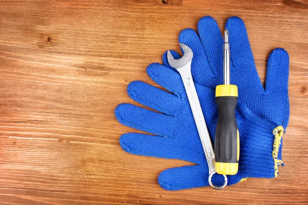 Schraubenschlüssel und Schraubenzieher mit Handschuhen auf Holzgrund — Stockfoto