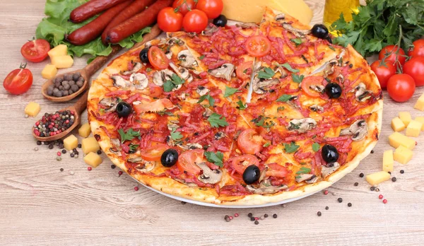 Deliciosa pizza, legumes e salame na mesa de madeira — Fotografia de Stock