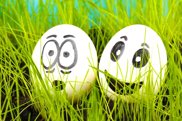 Huevos blancos con caras graciosas en hierba verde —  Fotos de Stock
