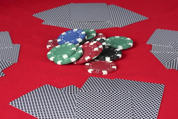 Poker fişleri ve oyun kağıtları kırmızı bir tablo — Stok fotoğraf