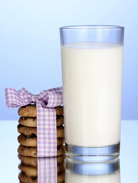 Vaso de leche y galletas sobre fondo azul —  Fotos de Stock