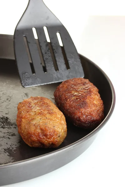 Hambúrgueres saborosos na panela no fundo branco close-up — Fotografia de Stock