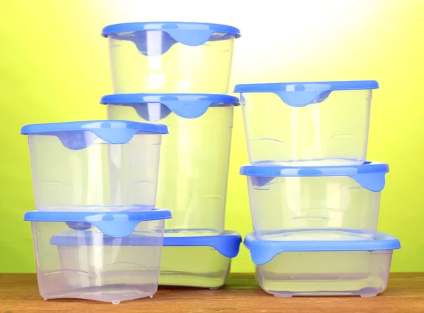 Kunststoffbehälter für Lebensmittel auf Holztisch auf grünem Hintergrund — Stockfoto