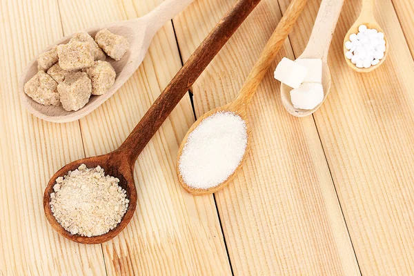 Edulcorante con azúcar blanca y morena en cucharas sobre fondo de madera — Foto de Stock