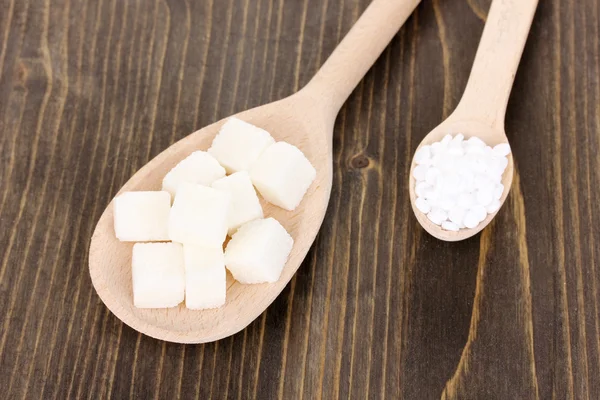 Edulcorante y azúcar blanco en cucharas sobre fondo de madera — Foto de Stock