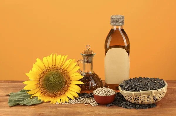 Sonnenblumenöl und Sonnenblumen auf gelbem Hintergrund — Stockfoto