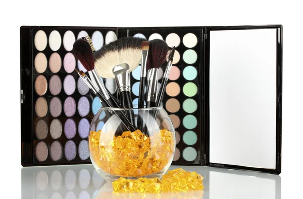 Make-up brushes in a bowl with stones on palette of shadows background — Stock Photo, Image