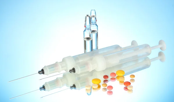 Syringes monovet, ampoules and pills on blue background — Stock Photo, Image