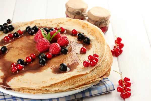 Leckere Pfannkuchen mit Beeren und Marmelade auf Teller auf Holztisch — Stockfoto