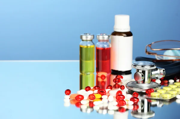 Лекарства и стетоскоп на синем фоне крупным планом — стоковое фото