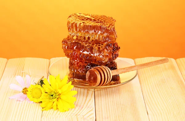 Favo de mel na mesa de madeira no fundo laranja — Fotografia de Stock