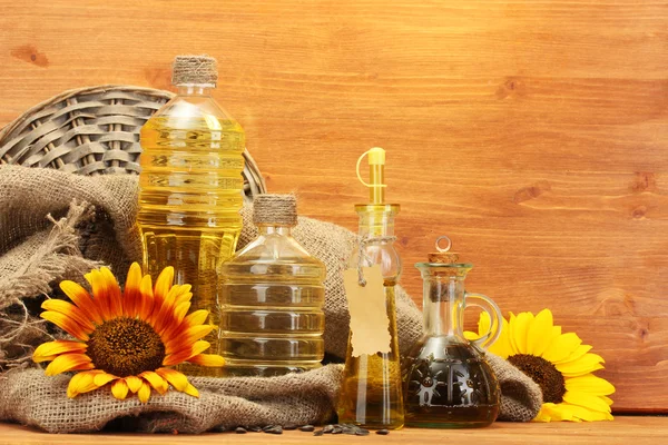 Óleo em garrafas, girassóis e sementes, sobre fundo de madeira — Fotografia de Stock