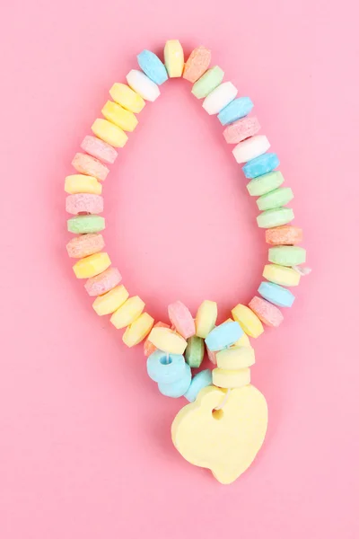 Caramelos de color sobre cuerda sobre fondo rosa — Foto de Stock