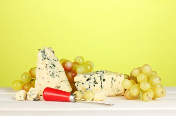 Композиция из голубого сыра и винограда на зеленом фоне крупным планом — стоковое фото