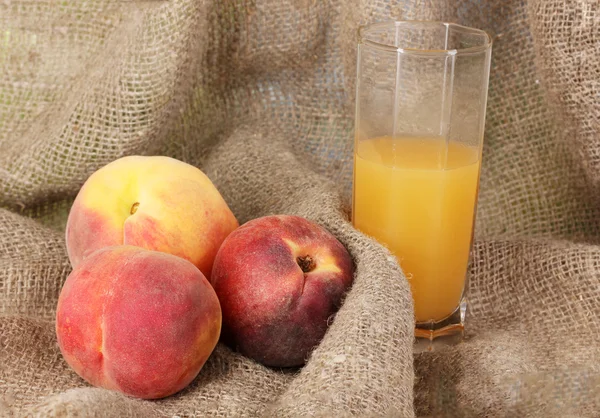 Mogna persikor och juice på säckväv — Stockfoto