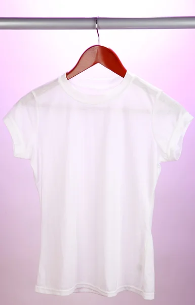 Белая футболка на вешалке на розовом фоне — стоковое фото