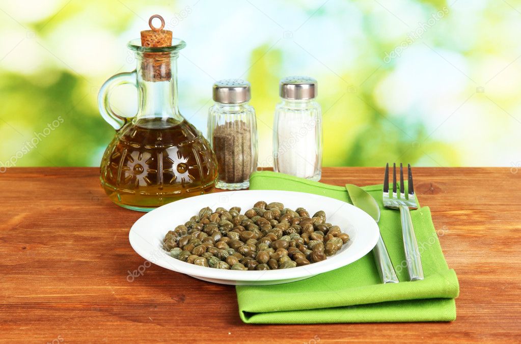Capers in the plate on bright green background