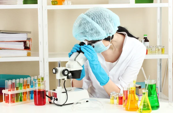 Científica joven mirando el microscopio en el laboratorio de química — Foto de Stock