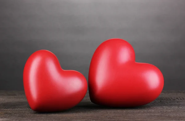 Twee decoratieve rode hartjes op houten tafel op grijze ondergrond — Stockfoto
