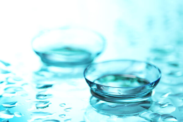 Contact lens with drops on blue background