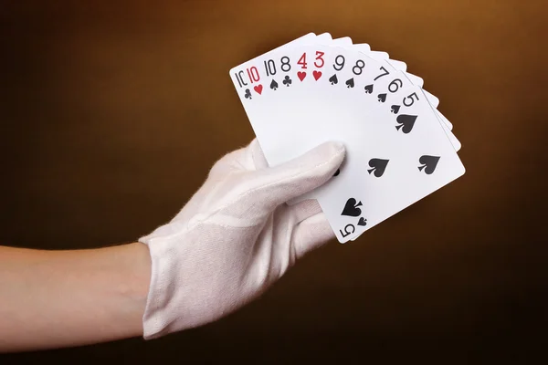 Cards in hand on brown background — Stock Photo, Image