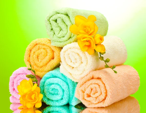 Πολύχρωμο πετσέτες και λουλούδια σε πράσινο κίτρινο φόντο — Φωτογραφία Αρχείου