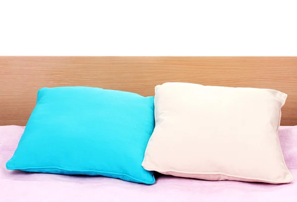 Světlé polštáře na posteli na bílém pozadí — Stock fotografie