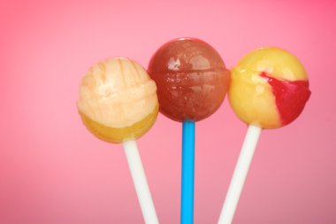 Bright and delicious lollipops on pink background close-up clipart