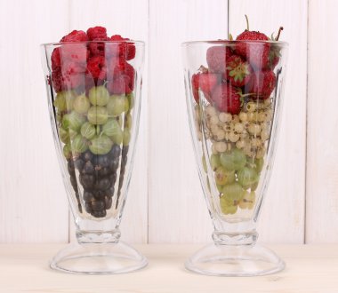 Mixed fruits and berries in glasses on wooden background