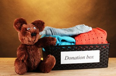 Donation box with clothing on brown background close-up clipart