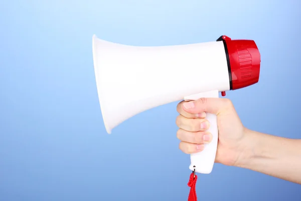 Red and white megaphone in hand on blue background — Stock Photo, Image