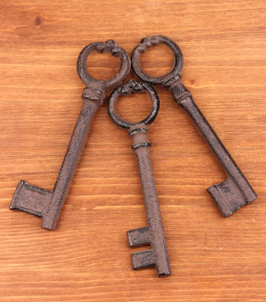 Drei antike Schlüssel auf Holzgrund — Stockfoto