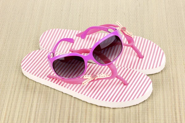 Pink beach slippers with sunglasses on mat — Stock Photo, Image