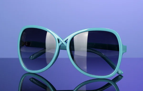 Óculos de sol azuis femininos na moda em fundo colorido brilhante — Fotografia de Stock