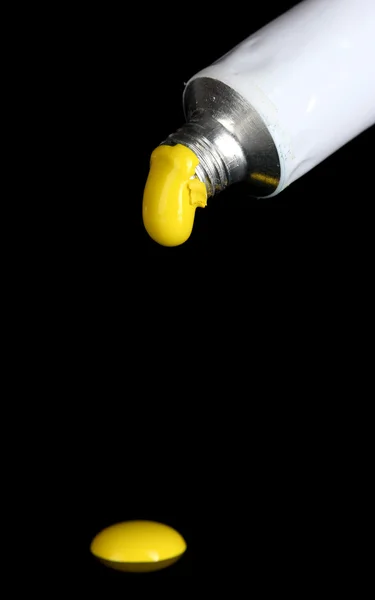 Желтая краска следует из трубки на черном фоне крупным планом — стоковое фото