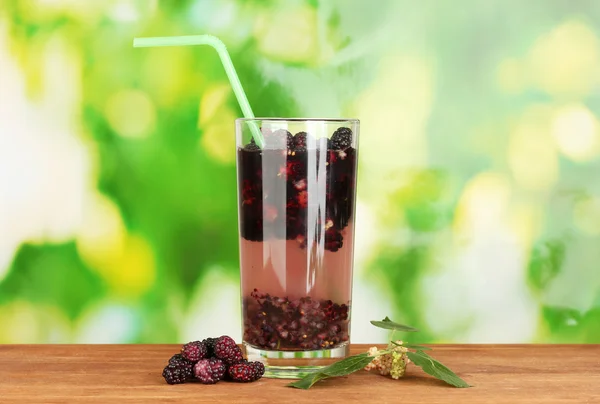 Glass of refreshing mulberry juice on wooden table on green background close-up — Stock Photo, Image
