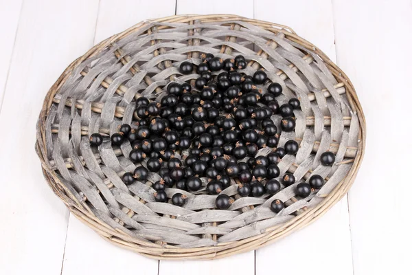 Black currant on wicker mat on wooden background — Stock Photo, Image