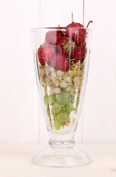 Blandade frukter och bär i glas på trä bakgrund — Stockfoto