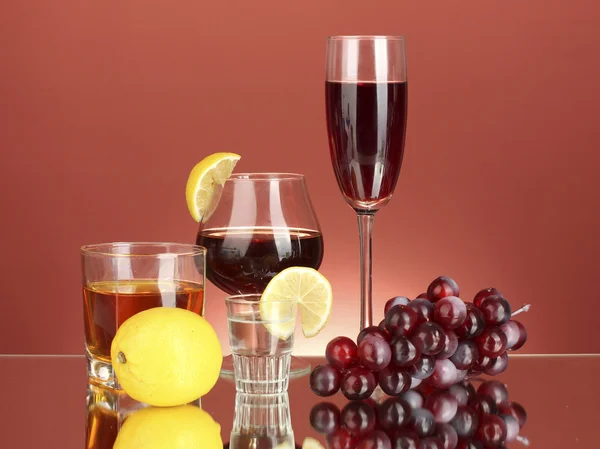 Olika alkoholhaltiga drycker på röd bakgrund — Stockfoto