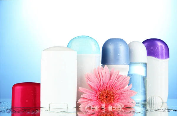 Botellas de desodorante con flor sobre fondo azul —  Fotos de Stock