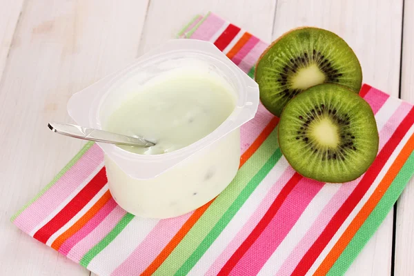 Yoghurt met kiwi op servet op houten achtergrond — Stockfoto